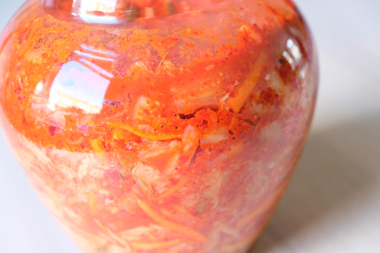 Kimchi in a chinese fermentation jar with air bubbles forming